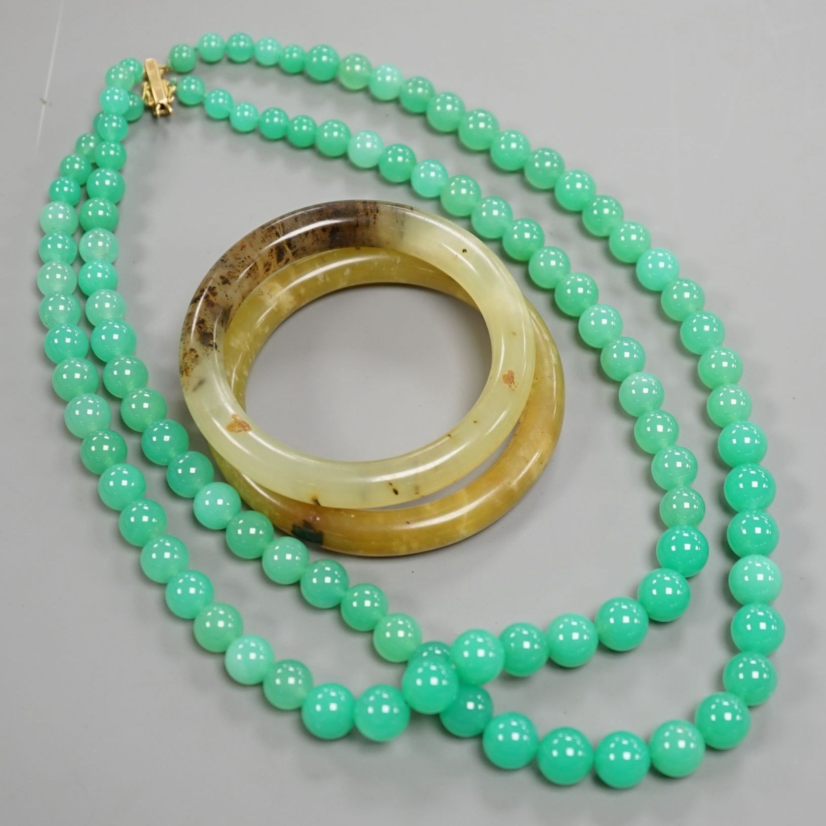 A double strand chrysoprase bead necklace with 750 yellow metal clasp, 50cm and two bowenite bangles.